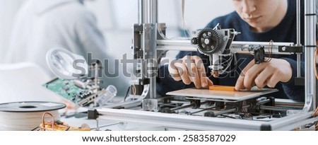 Young smart student working with a 3D printer in the lab, he is printing a prototype