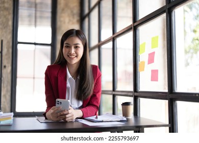 Young smiley attractive, businesswoman using sticky notes in glass wall to writing strategy business plan to development grow to success - Shutterstock ID 2255793697