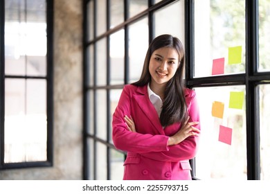 Young smiley attractive, businesswoman using sticky notes in glass wall to writing strategy business plan to development grow to success - Shutterstock ID 2255793715