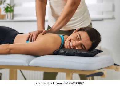 Young Smiley Woman in blue top laying down on table, having chiropractic adjustment. Osteopathy, Alternative medicine, pain relief concept. Physiotherapy                