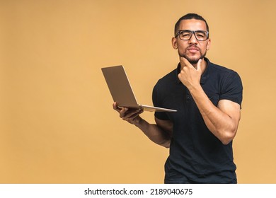 Young Smiling African American Black Man Standing And Using Laptop Computer Isolated Over Beige Background.