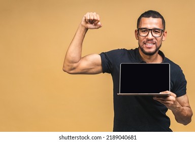 Young Smiling African American Black Man Standing And Using Laptop Computer Isolated Over Beige Background. Showing Pc Screen.