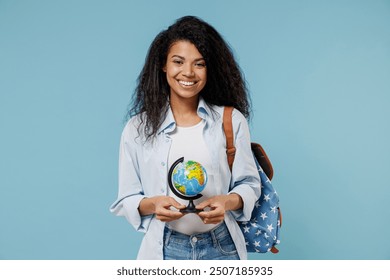 Young smiling african american girl teen geography student wear denim clothes backpack hold in hands Earth world globe isolated on blue background Education in high school university college concept - Powered by Shutterstock