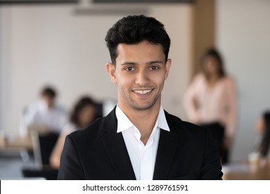 Young Smiling Arabic Businessman In Suit Looking At Camera In Office With Team At Background, Successful Manager, Arab Millennial Corporate Employee Leader, Happy Coach Executive Head Shot Portrait