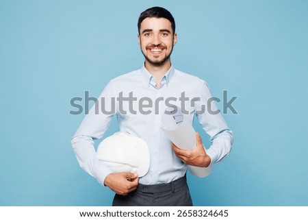 Young smiling architect engineer designer employee man wear white clothes shirt hardhat hold blueprints look camera isolated on plain light blue background studio portrait People work on build project