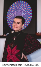 Young And Smiling Artist Girl With Very Short Hair, Bindi And Wool Sweater In Front Of His Beautiful Abstract Circle Painting