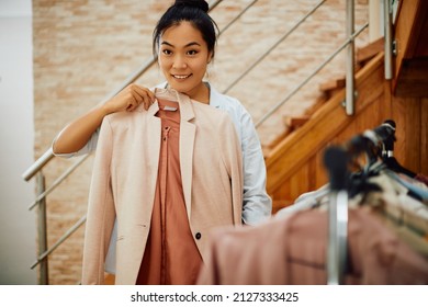 Young Smiling Asian Woman Choosing Her Outfit While Getting Dressed At Home. 