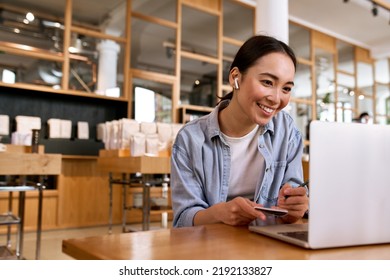 Young smiling Asian woman student using laptop computer wearing earbud, taking notes watching online class elearning webinar training, having hybrid remote video call or virtual work interview. - Powered by Shutterstock