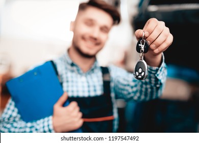 Young Smiling Auto Mechanic With Car Keys And Tablet Desk. Professional Uniform. Service Station Concept. Confident Engineer Stare. Smiling Repairman Staring. Working In The Garage.