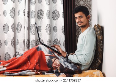 Young Smiling Bearded Indian Boy Sit On Bed In Bedroom Makes Video Call Looks At Camera Conversation By Distant Video Call, Distance Hiring Job Interview Process Tutor And Trainee Study Online Concept