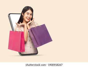 Young Smiling Beautiful Asian Woman Making Online Shopping And Holding Shopping Bags Out Through Mobile Phone Isolated On Beige Background With Clipping Path.