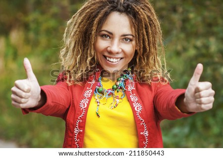 Young smiling beautiful woman with dreadlocks in red dress shows that everything is fine.