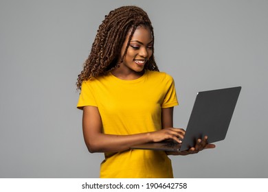 Young smiling black woman standing with laptop computer isolated on white background