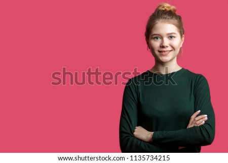 Young smiling blond woman in casual clothing against pink wall with copyspace area for advertise text or slogan. Caucasian female model with hairbun in optimistic, positive mood. happy feeling