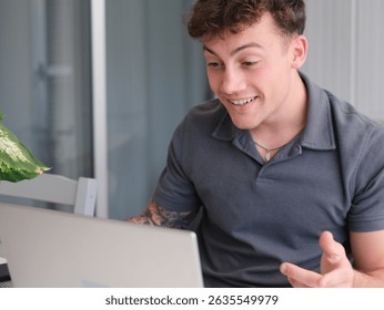 Young smiling boy while using his computer webcam in video chat. A laptop is open in front of him, suggesting he might be working or studying remotely