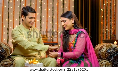 Young smiling brother and sister celebrating Raksha Bandhan together - Tying rakhi, Indian Model. Cheerful sister tying rakhi on her brother's wrist on the occasion of Raksha Bandhan 