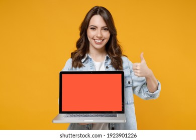 Young Smiling Brunette Fun Woman 20s Wear Denim Shirt White T-shirt Hold Laptop Pc Computer With Blank Screen Workspace Area Show Thumb Up Like Gesture Isolated On Yellow Background Studio Portrait.