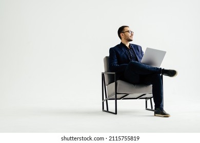 Joven empresario sonriente sentado en una silla de oficina y trabajando en una computadora portátil aislada de fondo blanco