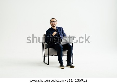 Young smiling businessman sitting in office chair and working on laptop computer isolated on white background