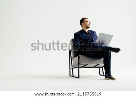 Young smiling businessman sitting in office chair and working on laptop computer isolated on white background