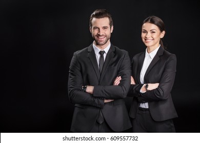 Young smiling businesspeople with crossed arms looking at camera  isolated on black - Shutterstock ID 609557732