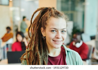 Young smiling businesswoman or designer in casualwear standing in front of camera against her intercultural colleagues working in open space - Powered by Shutterstock