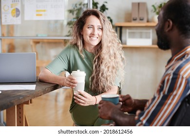 Young smiling businesswoman drinking coffee with her colleague at office during coffee break - Powered by Shutterstock