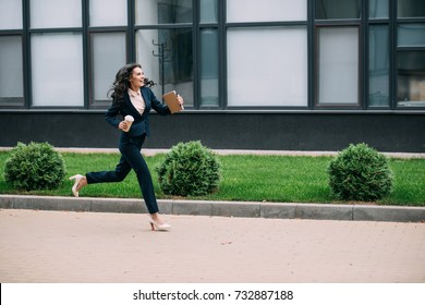 Young Smiling Businesswoman Running To Work With Coffee And Notebook