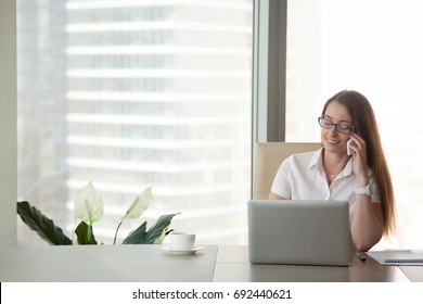 Young Smiling Businesswoman Talking On The Phone At Workplace, Happy Office Worker Making Business Or Personal Call Sitting At Work Desk, Checking Cell Voicemail, Corporate Mobile Communications