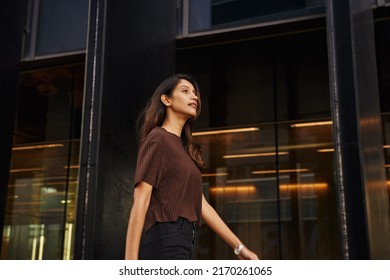 Young smiling businesswoman walking on city street looking away - Shutterstock ID 2170261065