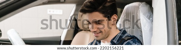 Young smiling car mechanic testing car while\
working in garage indoors