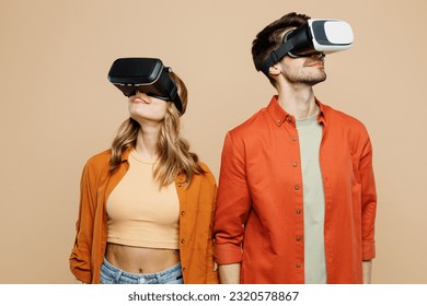 Young smiling caucasian happy couple two friends family man woman wear casual clothes together watching in vr headset pc gadget isolated on pastel plain light beige color background studio portrait - Powered by Shutterstock