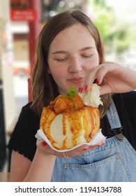 Young Smiling Caucasian Woman Tasting A Durban Bunny Chow Outdoors, Which Is A South African Fast Food Dish Consisting Of A Hollowed Out Loaf Of Bread Filled With Curry.