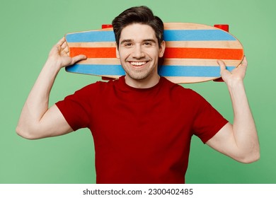 Young smiling cheerful caucasian happy fun man he wears red t-shirt casual clothes hold skateboard pennyboard behind neck look camera isolated on plain pastel light green background studio portrait - Powered by Shutterstock