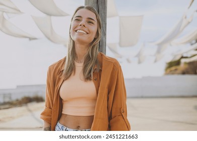 Young smiling cheerful fun cool minded calm woman she wearing orange shirt beige top casual clothes look aside in reverie mood rest relax walk outside in summer day. Urban lifestyle leisure concept - Powered by Shutterstock