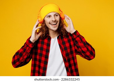 Young smiling cheerful happy caucasian man wearing red checkered shirt white t-shirt hat headphones listen to music look aside isolated on plain yellow background studio portrait. Lifestyle concept - Powered by Shutterstock