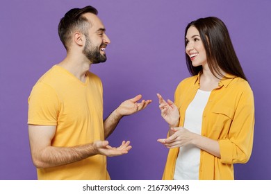 Young Smiling Cheerful Happy Cool Couple Two Friends Family Man Woman Together In Yellow Casual Clothes Look To Each Other Speak Talk Spead Hands Isolated On Plain Violet Background Studio Portrait