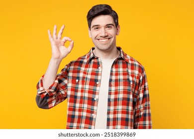 Young smiling cheerful satisfied happy Caucasian man he wears red checkered shirt casual clothes looking camera showing ok okay gesture isolated on plain yellow orange background. Lifestyle concept - Powered by Shutterstock