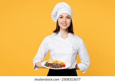 Young smiling chef cook baker woman wear white shirt black apron uniform toque chefs hat hold in hand plate give ready order dish steak isolated on plain yellow background studio. Cooking food concept - Powered by Shutterstock