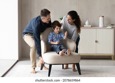 Young smiling couple carrying armchair where sit little son. Happy homeowners family placing delivered furniture at relocation day. Realty, real estate, bank loan, modern furnishing store ad concept - Shutterstock ID 2078659864