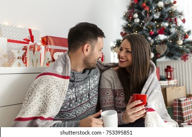 Young Smiling Couple Drinking Coffee And Enjoying Christmas Morning