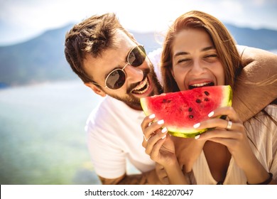 Young smiling couple eating watermelon on the beach having fun. - Powered by Shutterstock