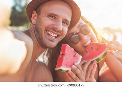 Young Smiling Couple Eating Watermelon On The Beach Having Fun, Taking Selfie, Golden Hour