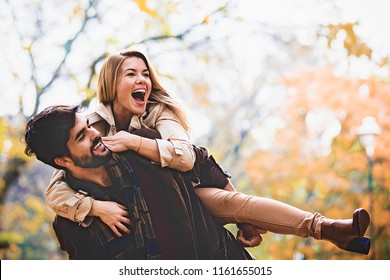 Young Smiling Couple Enjoying Fall In The Park.