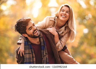 Young Smiling Couple Enjoying Fall In The Park.