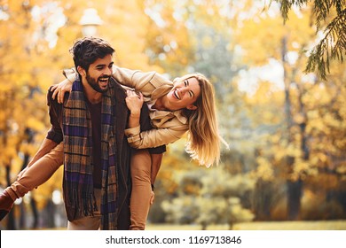 Junge lächelnde Paare, die Spaß im Park fallen.