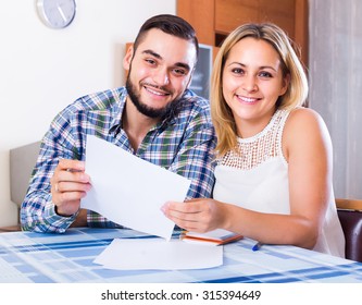 Young Smiling Couple Filling Forms For Joint Banking Account At The Table
