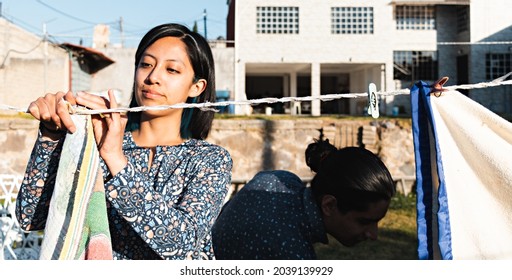 Young Smiling Couple Hanging Out Clothes In The Backyard