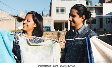 Young Smiling Couple Hanging Out Clothes In The Backyard