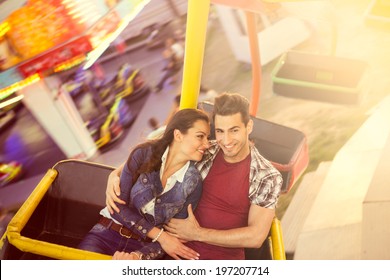 Young Smiling Couple Having A Ride On A Ferris Wheel